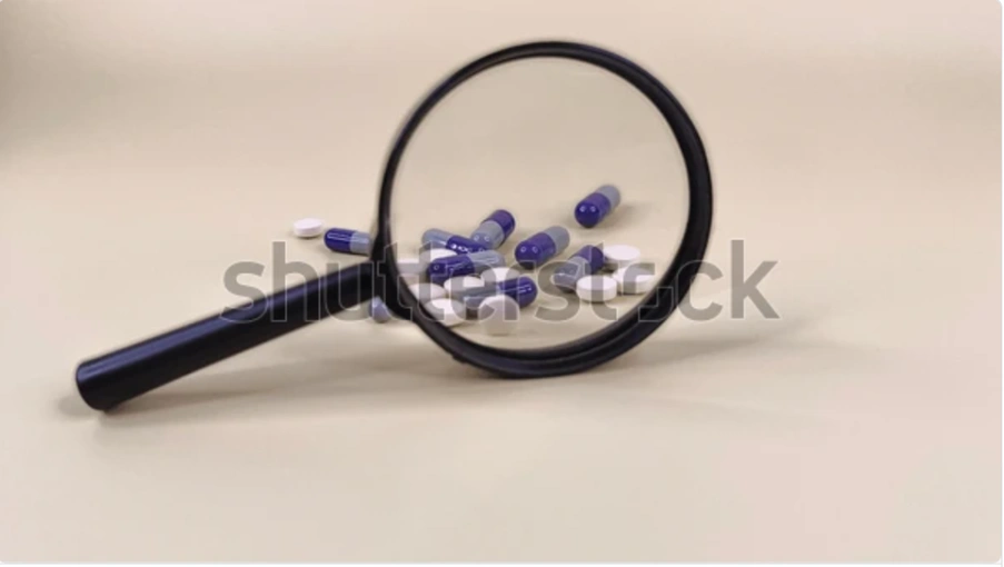 Close-up of pills seen through a magnifying glass, symbolizing dose optimization in oncology under Project Optimus.